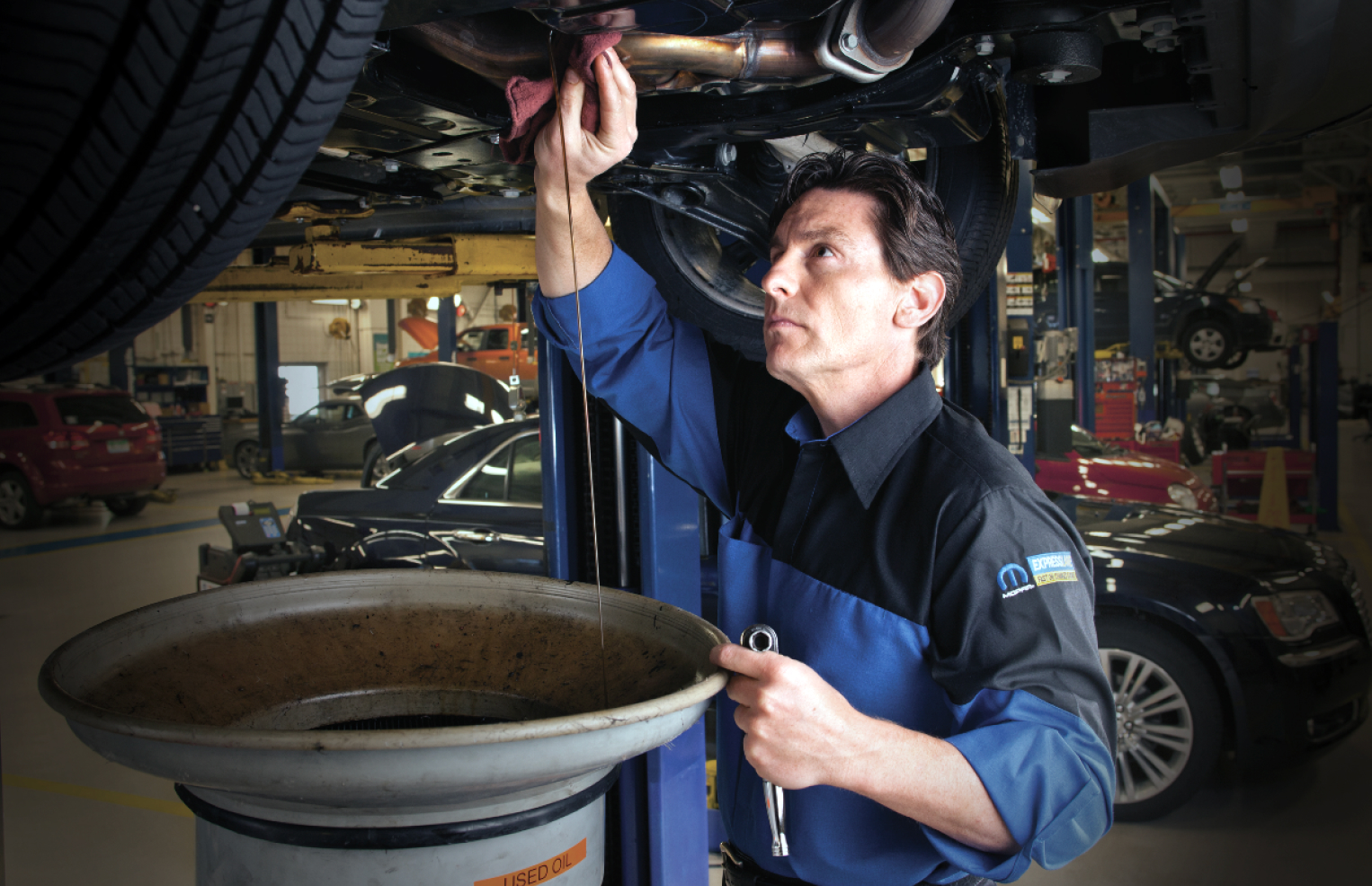 Mopar technician draining oil out of a vehicle during an oil change