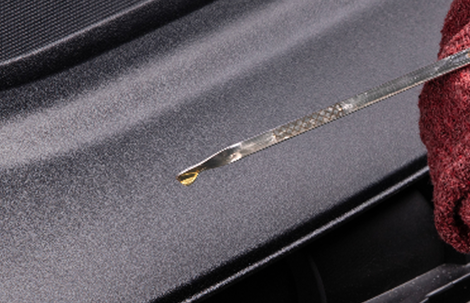 Hand holding dipstick and rag checking oil level