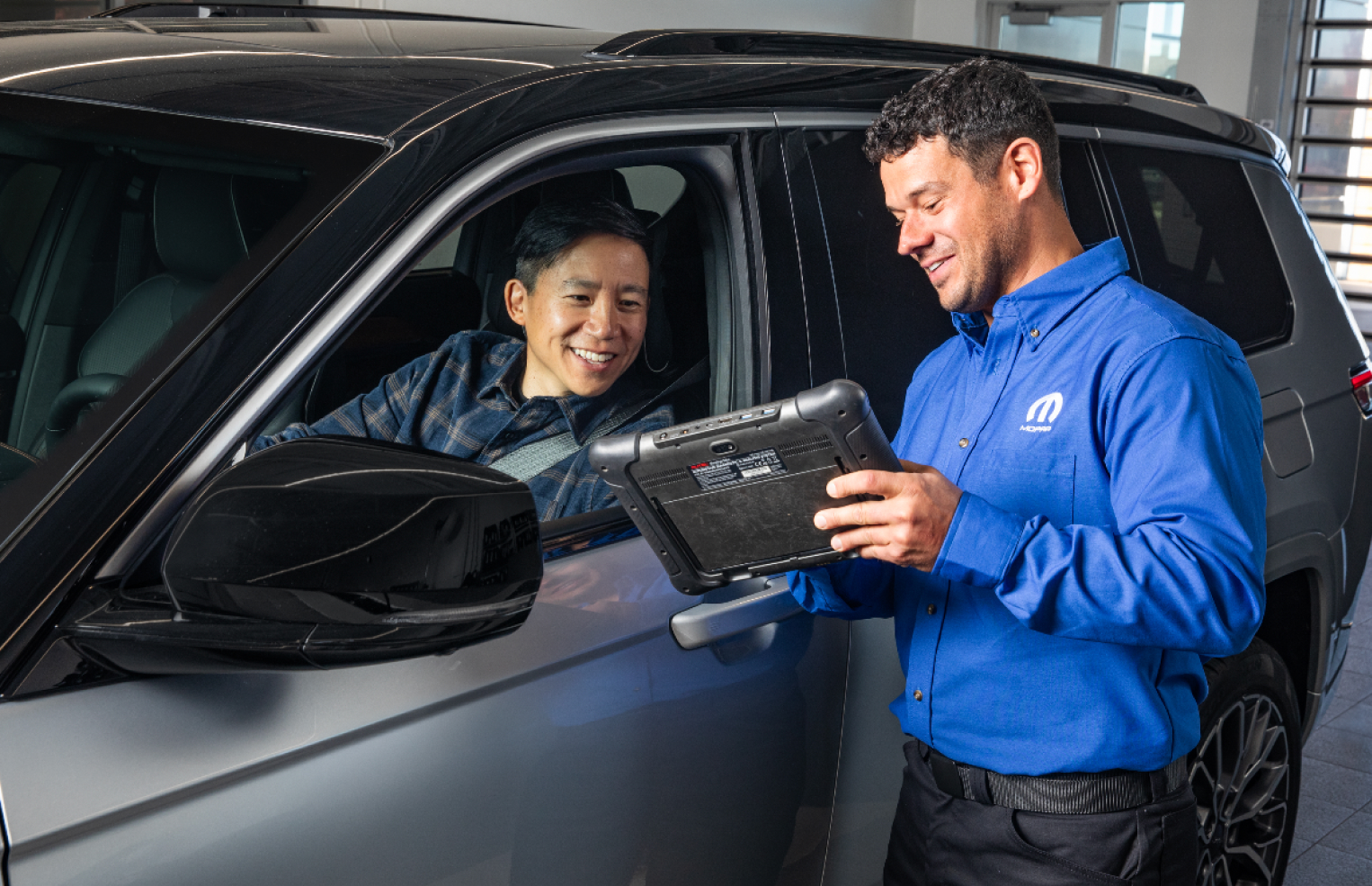 Service advisor showing something to a customer on a tablet in an Mopar Express Lane
