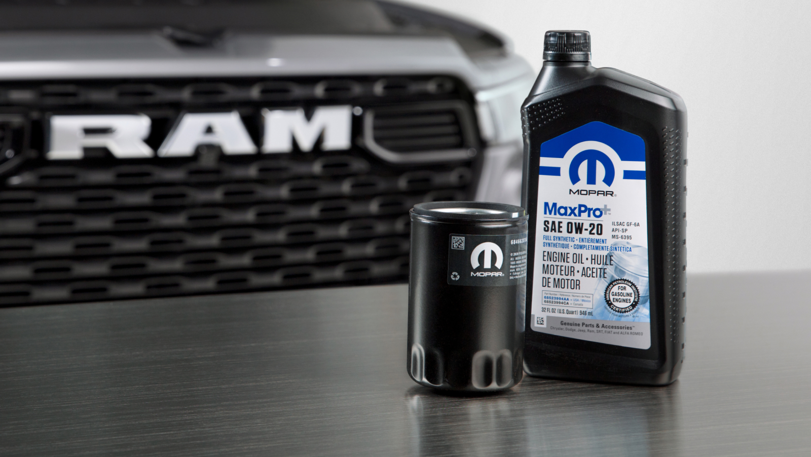 Mopar oil and oil filter on a table in front of a silver Ram pickup