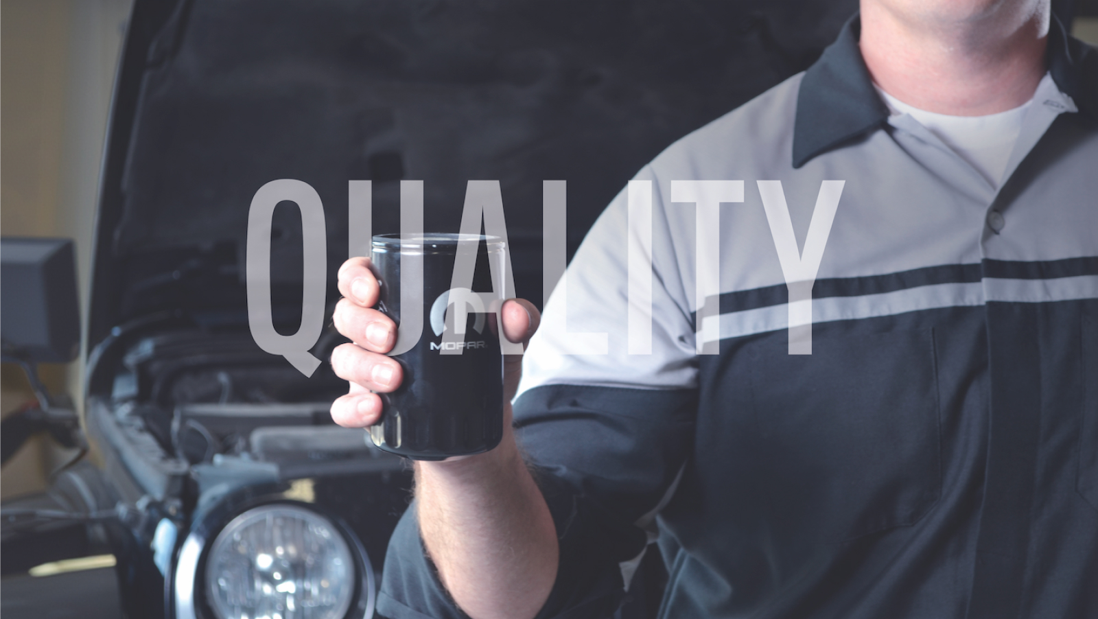 technician holding a Mopar oil filter in front of a Jeep with the word QUALITY in white over the image