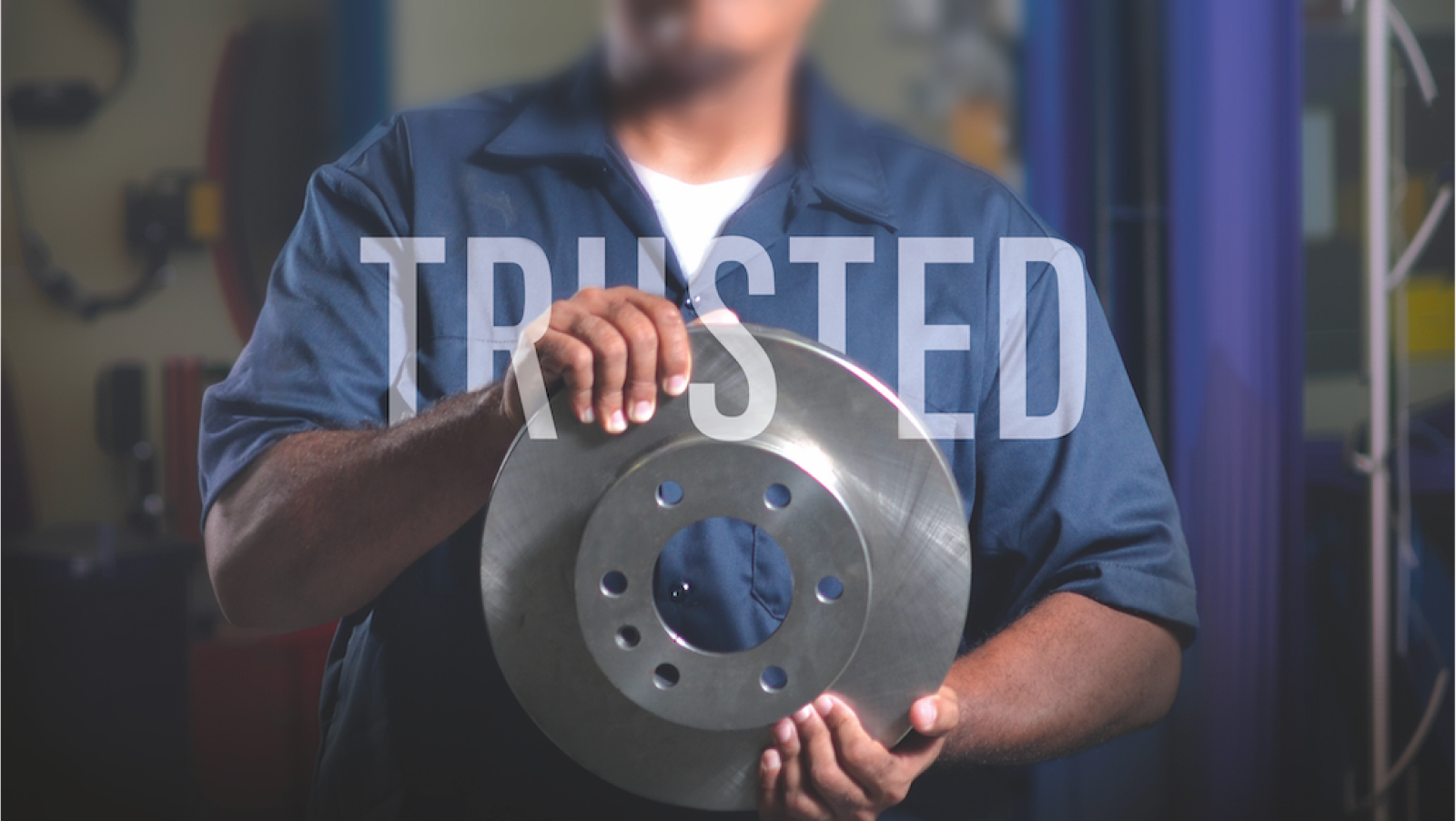 technician holding a Mopar brake rotor with the word TRUSTED in white over the image