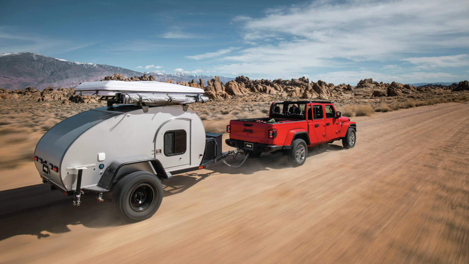 2024 Gladiator Sport S in Firecracker Red pulling small trailer on desert dirt road