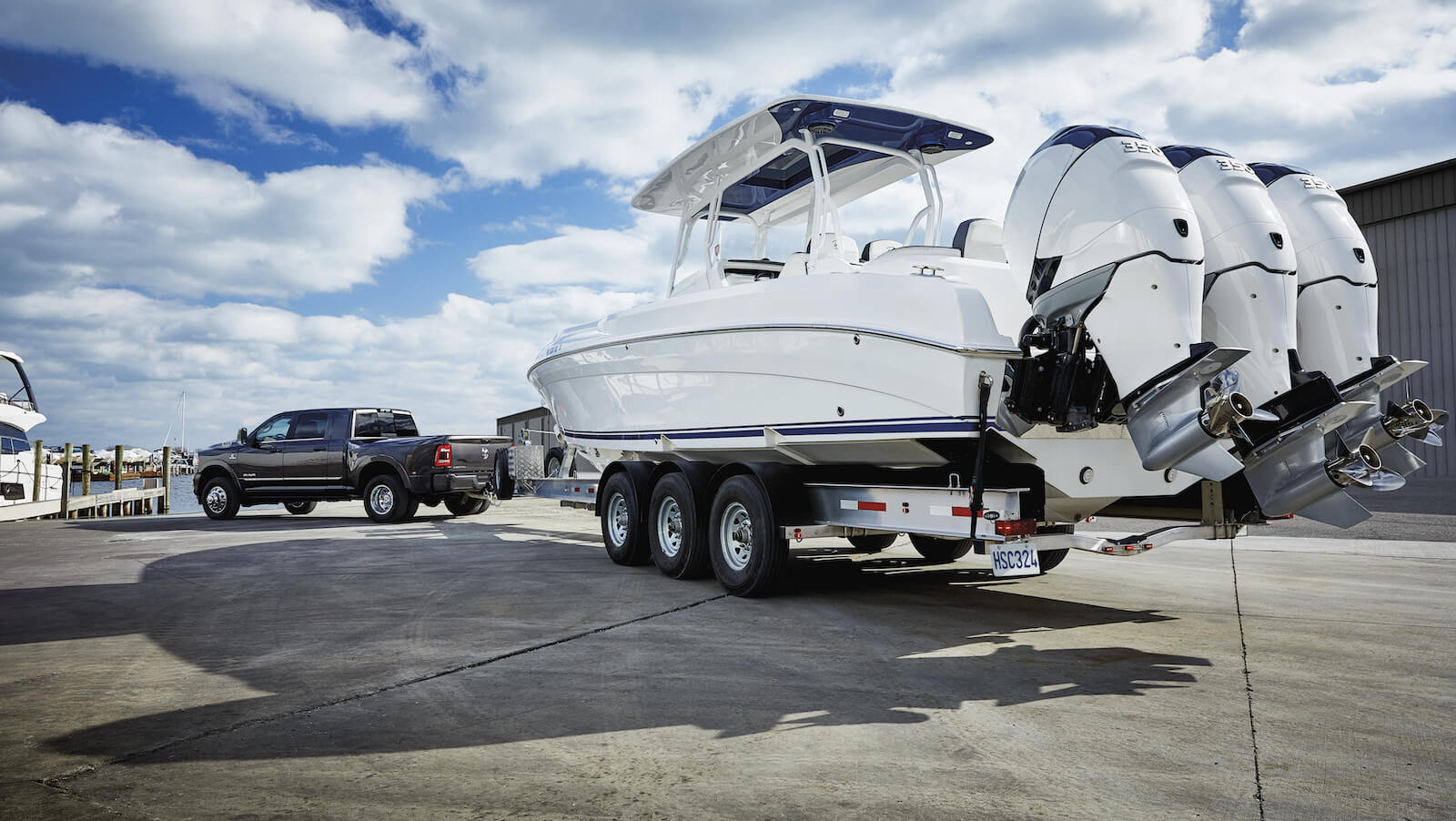 2023 Ram 3500 Limited Dually in Granite Crystal Pearl with large fishing boat in tow, parked at a marina