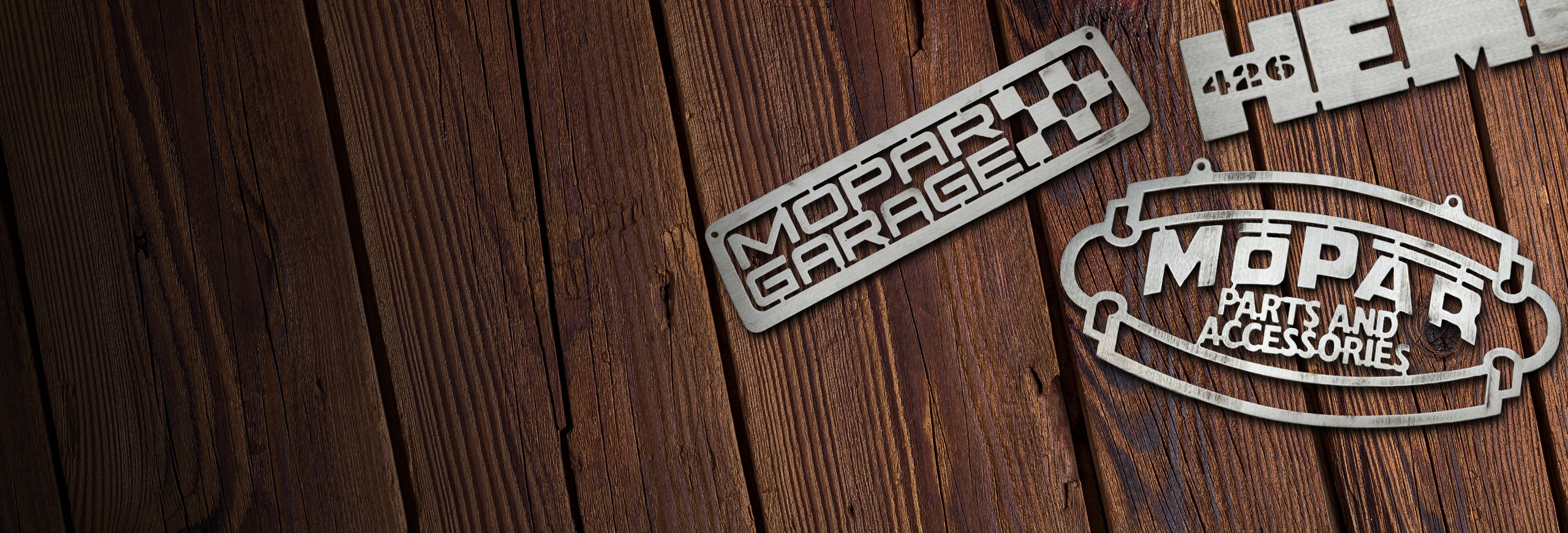 A set of three badges, sitting on a wood surface—a Mopar Garage badge, Mopar Parts and Accessories badge and a Hemi 426 badge.